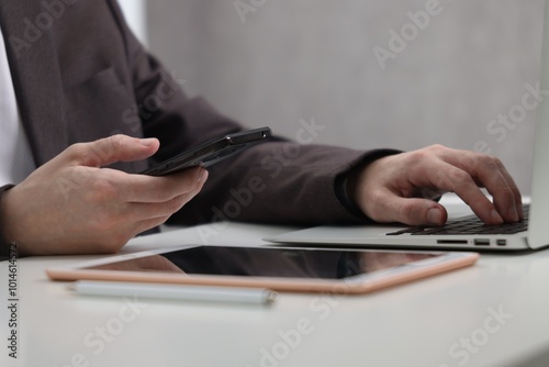 Businessman using different devices at white table indoors, closeup. Modern technology