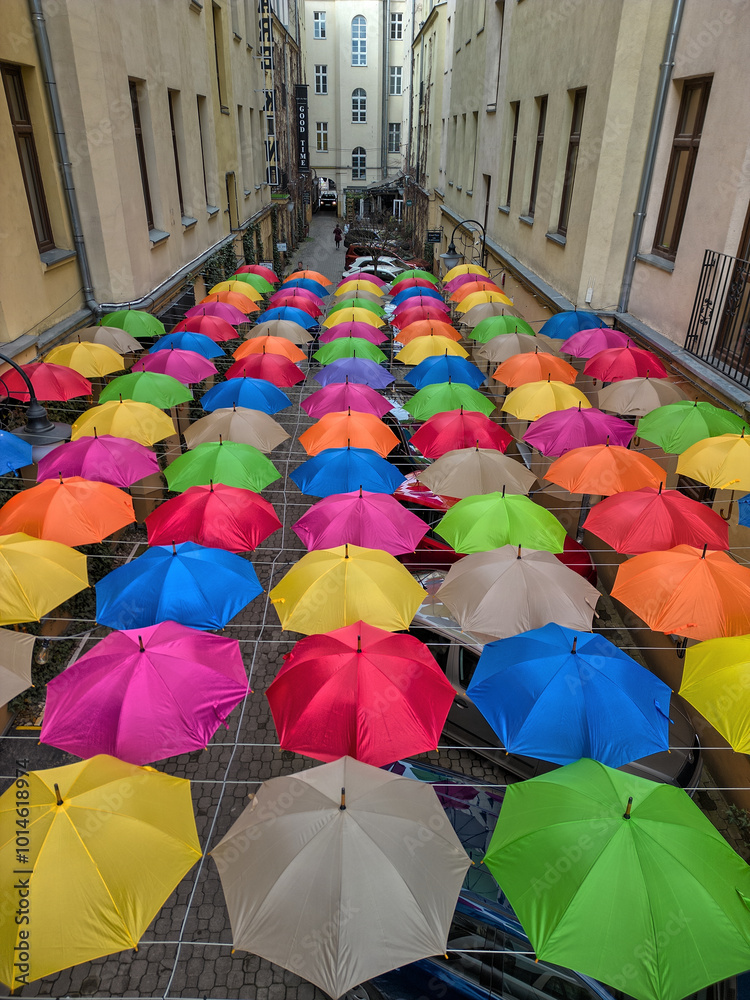 Vibrant Overhead Display of Multicolored Umbrellas Hanging Between Two Buildings in a Narrow Urban Courtyard in Łódź, Poland