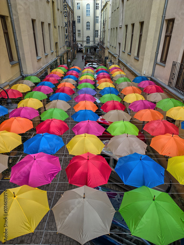Obraz na płótnie Vibrant Overhead Display of Multicolored Umbrellas Hanging Between Two Buildings in a Narrow Urban Courtyard in Łódź, Poland w salonie