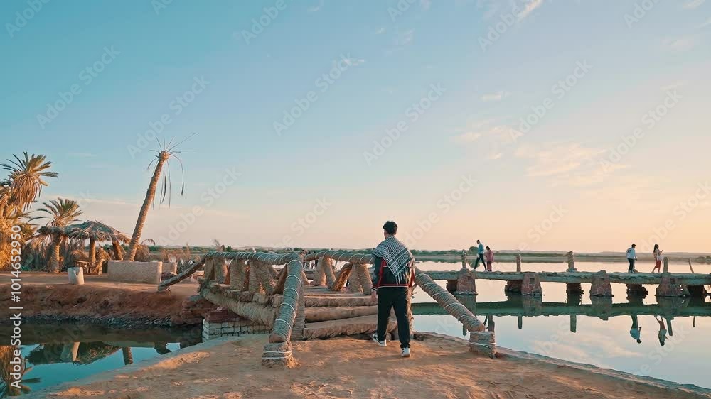 a young man traveler walking alone over the bridge exploring fatnas island in siwa oasis in egypt at sunset, siwa oasis, Egypt. a young man traveler walking alone over the bridge exploring fatnas island in siwa oasis in egypt at sunset, siwa oasis, Egypt.