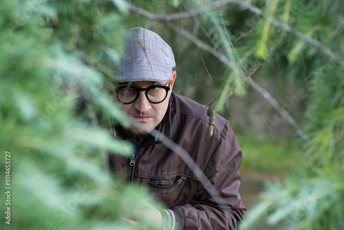 Creepy stalker hiding among the plants looks into camera photo