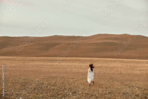 Wallpaper Mural Woman in white dress walking through open field with hills in background, embracing peace and serenity Torontodigital.ca
