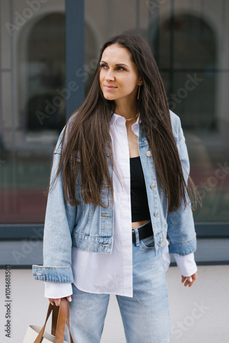 Photography Young woman wearing a blue jacket and jeans is standing in front of a building