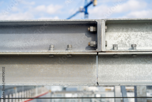 Galvanized bolted connection of steel elements of framework with blue tower crane in background
