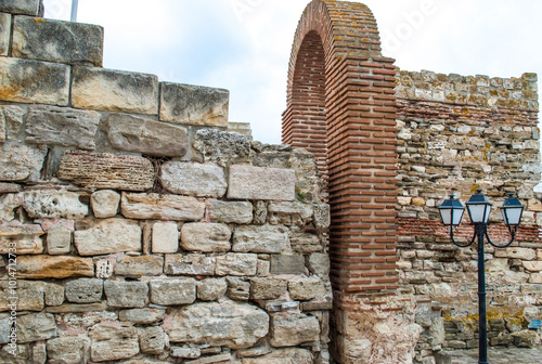 Fragment of a ruined fortress in the old town of Nessebar. A preserved stone wall with an arch