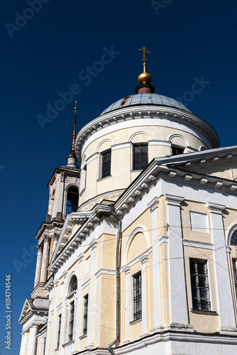 This image features an old Orthodox church with domes and a neoclassical design, including large columns and faded walls. The structure shows signs of wear, set against a bright sky and autumn trees. photo