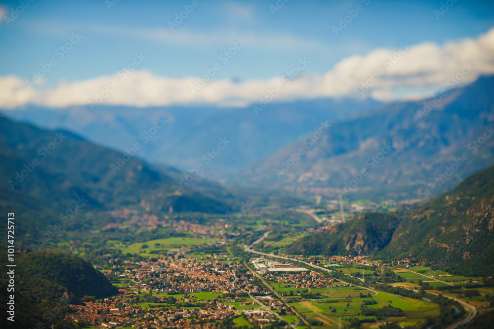 Obraz premium Panoramic landscape of the Italian city, photos from a drone, quadcopter, aerial photography. The city, the houses with tiled roofs, the road and the mountains. Layout. A miniature. View of Piedmont, 