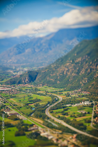 Panoramic landscape of the Italian city, photos from a drone, quadcopter, aerial photography. The city, the houses with tiled roofs, the road and the mountains. Layout. A miniature. View of Piedmont