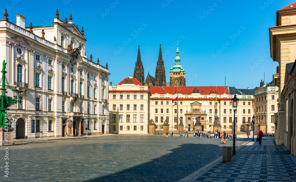 Fototapeta premium Cobblestone street winding through historic buildings in Prague with St. Vitus Cathedral. Street leads past historical buildings in Prague, showcasing the iconic spires of St. Vitus Cathedral, Prague.