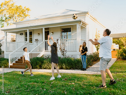 Family tossing a soccer ball inside their yard. photo