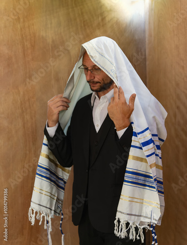 Konstfotografi Religious jew man wearing a black suit with a white shirt and is covered by a tallit, which is a Jewish prayer shawl with blue stripes and fringes