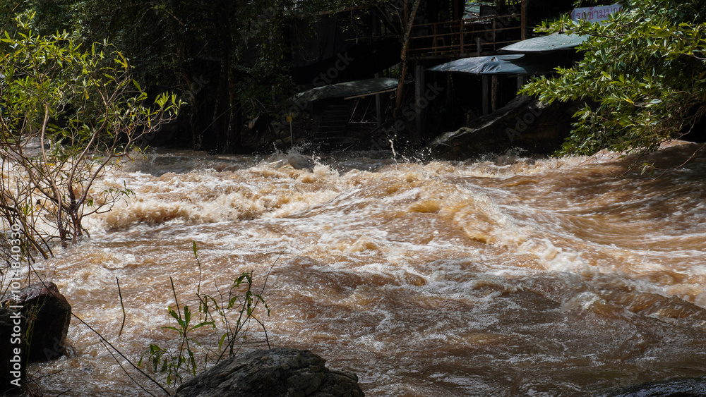Obraz premium A strong current near a waterfall. Floods flowing in mountain rivers after heavy rains. Flash floods, the effects of global warming and the effects of deforestation.