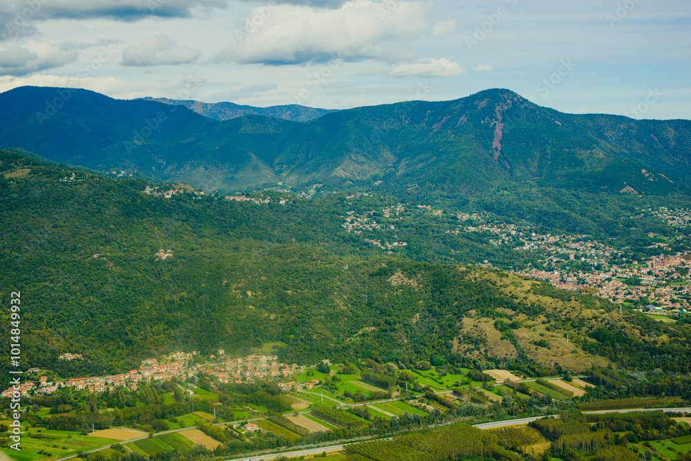 Fototapeta premium Panoramic landscape of the Italian city, photos from a drone, quadcopter, aerial photography. The city, the houses with tiled roofs, the road and the mountains. Layout. A miniature. View of Piedmont,
