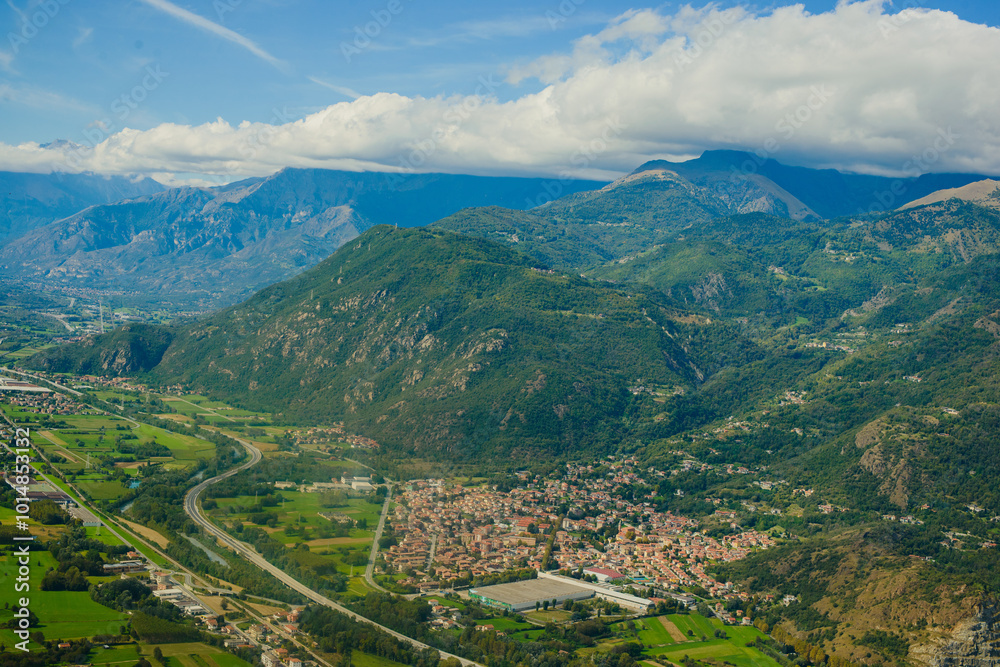 Obraz premium Panoramic landscape of the Italian city, photos from a drone, quadcopter, aerial photography. The city, the houses with tiled roofs, the road and the mountains. Layout. A miniature. View of Piedmont, 