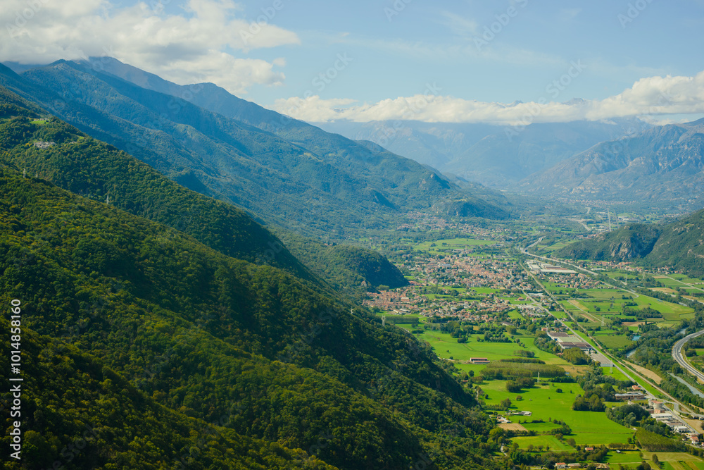 Fototapeta premium Panoramic landscape of the Italian city, photos from a drone, quadcopter, aerial photography. The city, the houses with tiled roofs, the road and the mountains. Layout. A miniature. View of Piedmont,