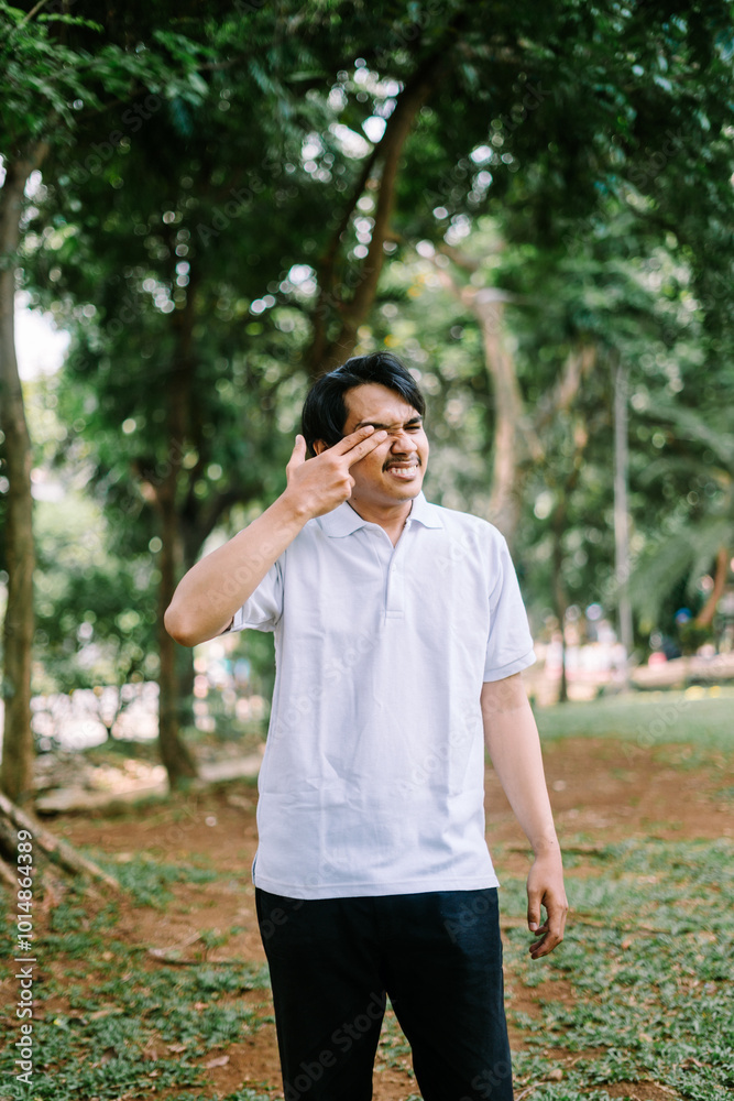 Southeast Asian man rubbing his eyes, expressing fatigue or discomfort. Southeast Asian man rubbing his eyes, expressing fatigue or discomfort.