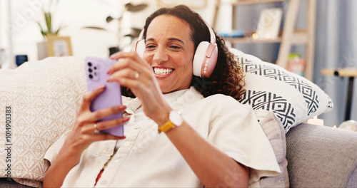 Sofa, happy woman and smartphone with headphone for music, audio track and change playlist in lounge. Female person, connection and cellphone with mobile app for chat, message or social media at home photo