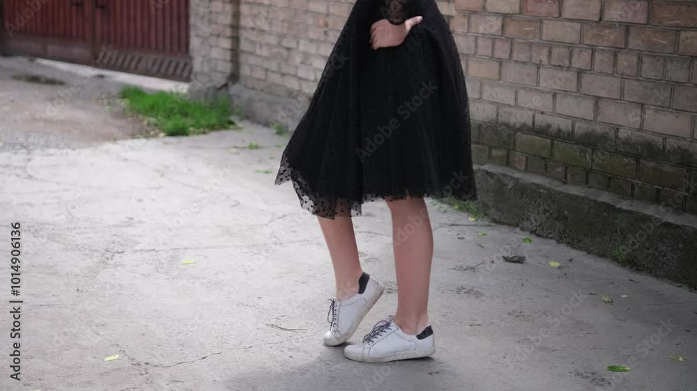 Beautiful young woman dancing gracefully on street. Elegant female dancer wearing black dress in city Beautiful young woman dancing gracefully on street. Elegant female dancer wearing black dress in city