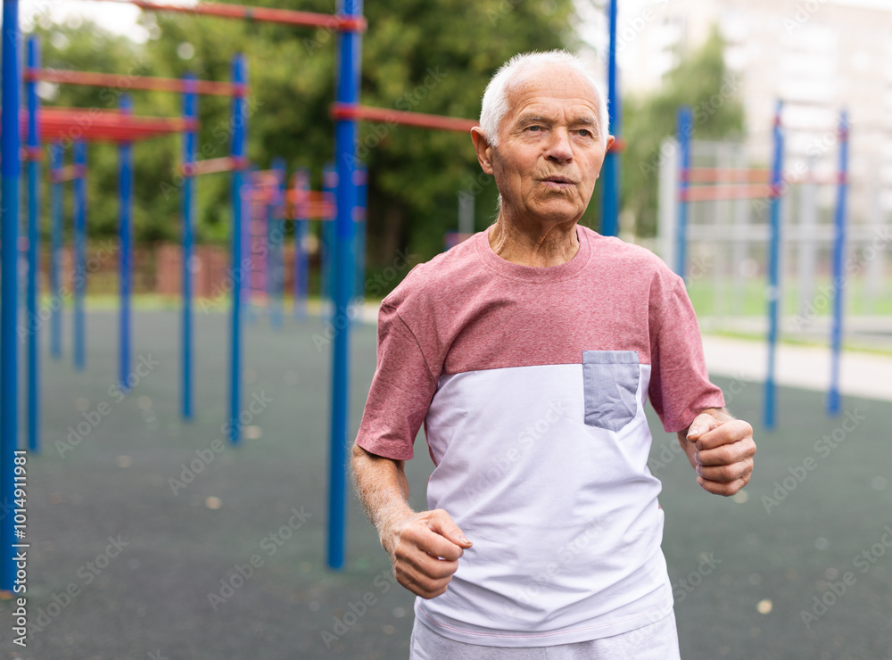 Old man running beside outdoor sports ground Old man running beside outdoor sports ground
