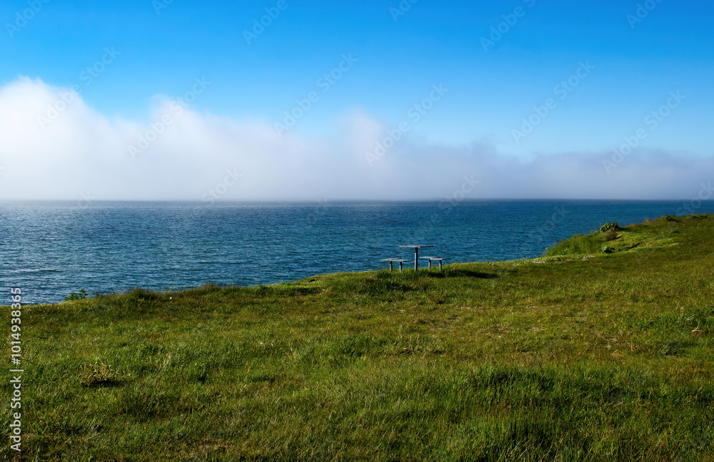 Picnic table in green grass overlooking the Baltic Sea on a spring day in northern Germany. Picnic table in green grass overlooking the Baltic Sea on a spring day in northern Germany.