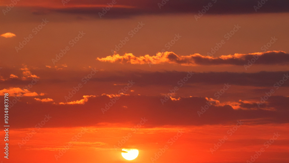 Fototapeta premium Vibrant red sunset with orange clouds and setting sun