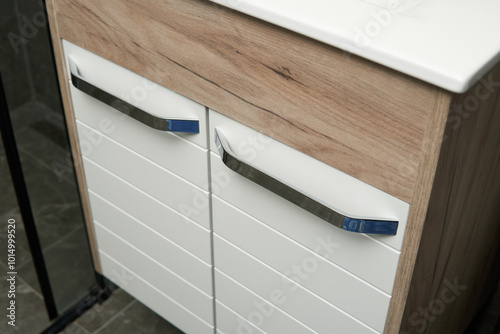 A modern bathroom vanity with a white cabinet and a wood-grain countertop