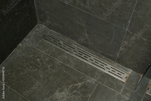 A stainless steel shower drain in a tiled bathroom photo