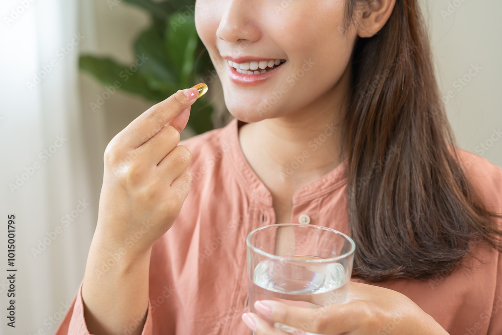 Dietary supplement, asian young woman, girl hand holding fish oil pills, drugs medical, take or eat vitamin for treatment skin, hair and nail strengthen with glass of water at home. Healthcare concept Dietary supplement, asian young woman, girl hand holding fish oil pills, drugs medical, take or eat vitamin for treatment skin, hair and nail strengthen with glass of water at home. Healthcare concept
