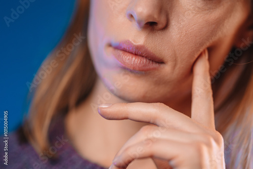Woman's face with her hand near it and finger touching cheek, closeup photo. Female in posture of thinking over something. Person thinking about making decision,
