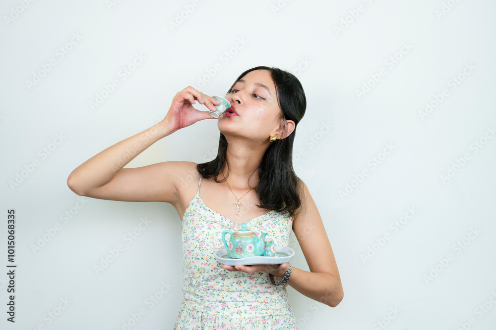 Young Asian girl drinking green tea from a Chinese teapot Young Asian girl drinking green tea from a Chinese teapot