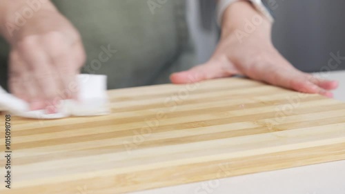 Hands wiping the wooden cutting board with a paper towel. Woman in the Kitchen Cleaning the Countertop, Preparing for Cooking Food.