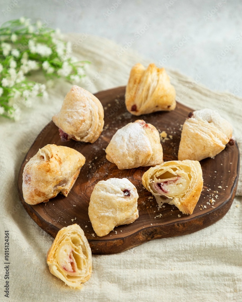 Delicious puff pastry cookies filled with strawberries and cream cheese lying on wooden board Delicious puff pastry cookies filled with strawberries and cream cheese lying on wooden board