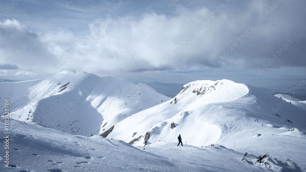 Hikers trekking through snowy ridgeline on overcast day during winter season. Hikers trekking through snowy ridgeline on overcast day during winter season.