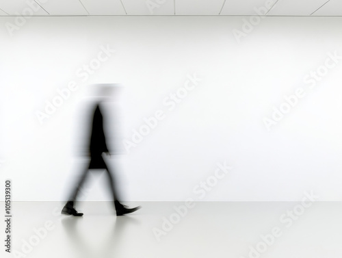 blurred silhouette of person walking in minimalist space, emphasizing motion and solitude. stark white background enhances feeling of emptiness and introspection