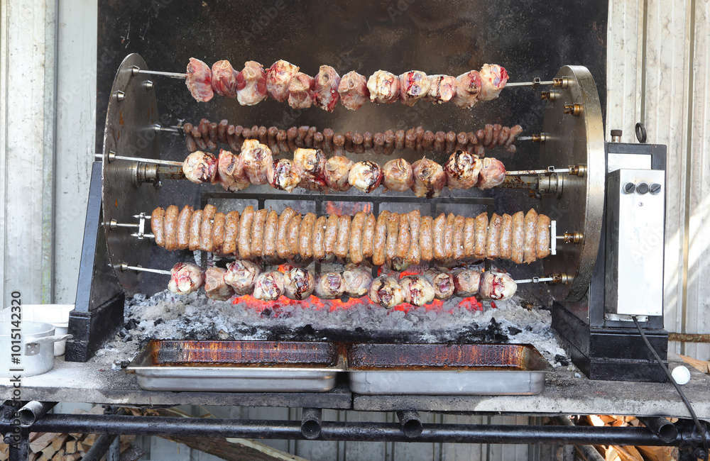 large spit loaded with grilled meat sausages and pork cooked over an open fire large spit loaded with grilled meat sausages and pork cooked over an open fire
