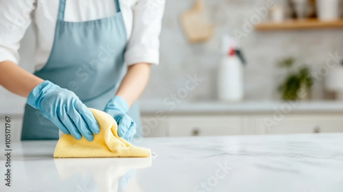 A person is cleaning kitchen countertop with yellow cloth, wearing blue gloves. scene conveys sense of cleanliness and care in home maintenance