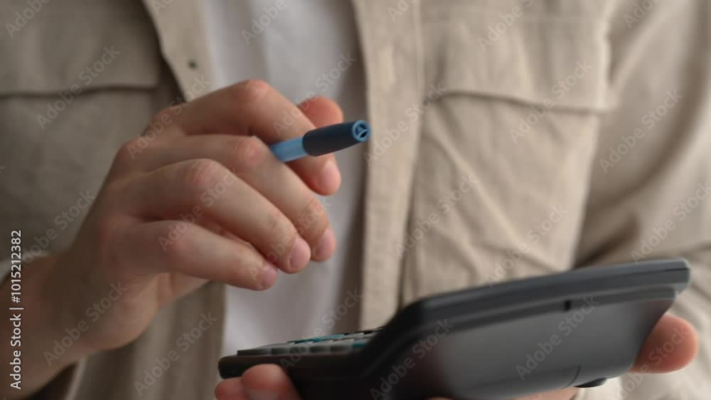 Young businessman using a calculator and laptop calculates expenses, income, money, counting bills, office documents, checking expenses, writing a business budget, accountant, financial work, calculat Young businessman using a calculator and laptop calculates expenses, income, money, counting bills, office documents, checking expenses, writing a business budget, accountant, financial work, calculat