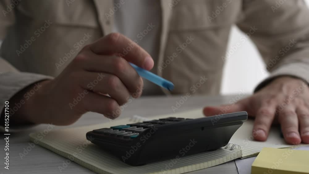 Young businessman using a calculator and laptop calculates expenses, income, money, counting bills, office documents, checking expenses, writing a business budget, accountant, financial work, calculat Young businessman using a calculator and laptop calculates expenses, income, money, counting bills, office documents, checking expenses, writing a business budget, accountant, financial work, calculat