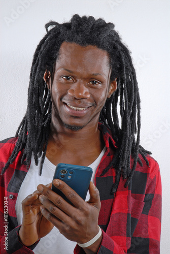 Cheerful African Rastafarian man using a cell phone