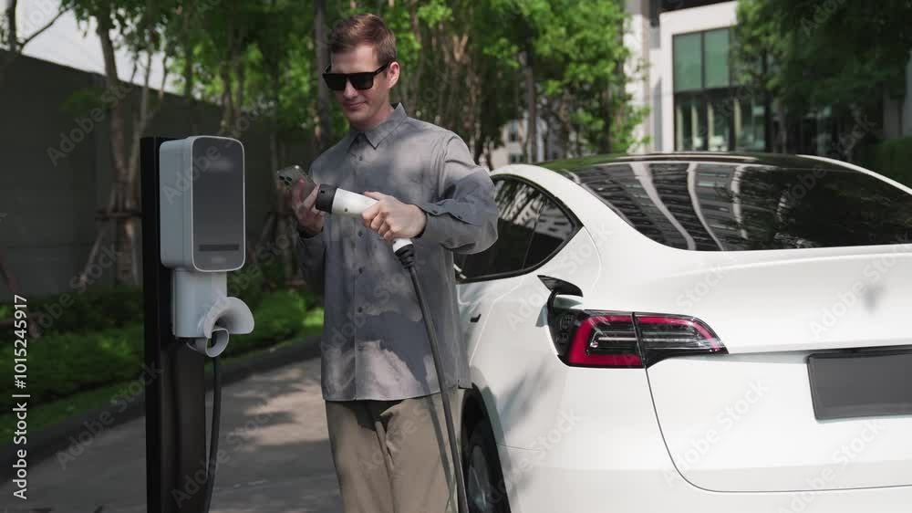 Slow motion man checks electric car battery charging status, range and charging limit on app screen. Smart technology device show EV car recharging data of electric storage in car battery innards.