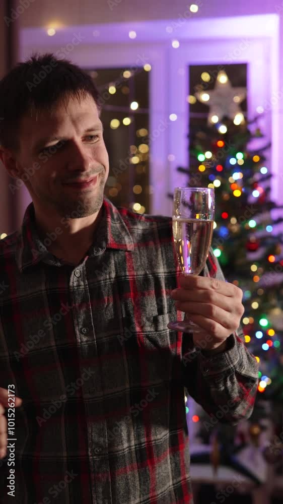 Lonely Caucasian man with glass of champagne in hand trying to enjoy holiday. Vertical video in decorated dark room with festive illumination and living moment. Lonely Caucasian man with glass of champagne in hand trying to enjoy holiday. Vertical video in decorated dark room with festive illumination and living moment.