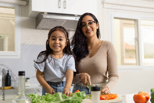 Latina Mother And Daughter Cooking Together In The Kitchen