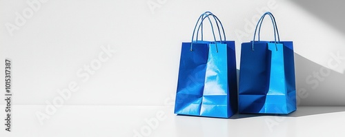 Two blue paper shopping bags on a plain white surface with subtle shadows and minimalist design photo