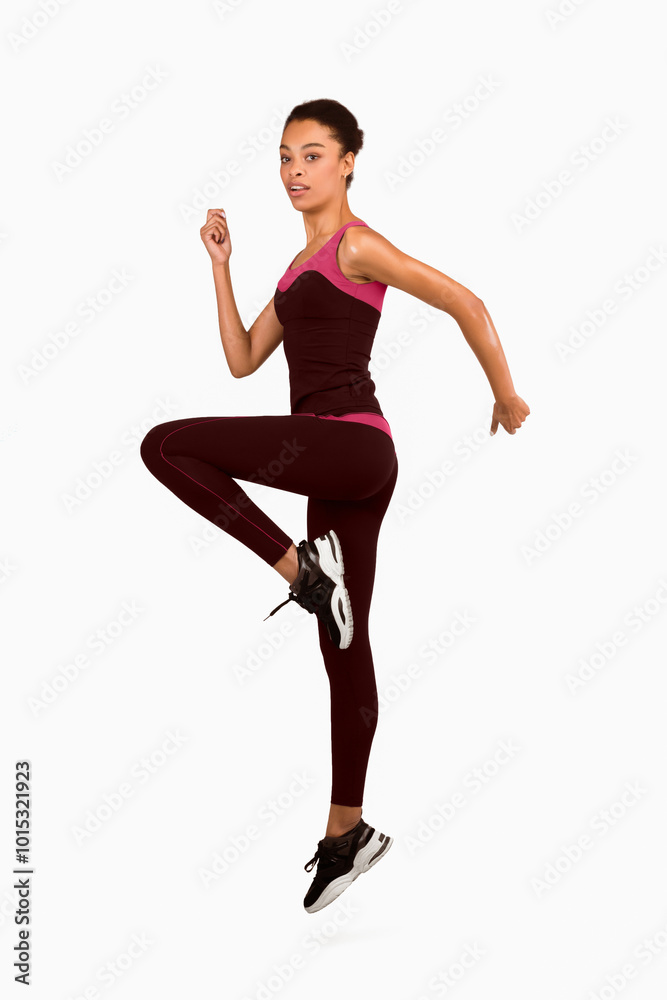 Fitness And Workout. Afro Girl Jumping Exercising During Sport Training Looking At Camera On White Studio Background. Vertical, Full Length Fitness And Workout. Afro Girl Jumping Exercising During Sport Training Looking At Camera On White Studio Background. Vertical, Full Length