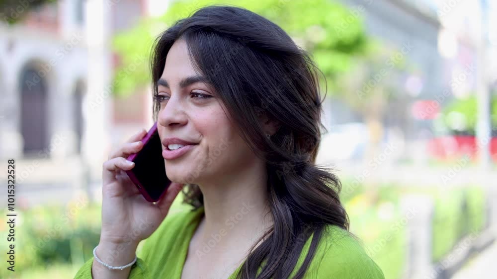 Beautiful, young Latin American woman walking down the street and talking on mobile phone Beautiful, young Latin American woman walking down the street and talking on mobile phone