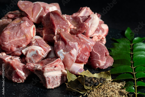 Freshly cut goat meat pieces with herbs and spices like bay leaves, cumin seeds, and peppercorns. Perfect for food preparation, recipes, and culinary projects.