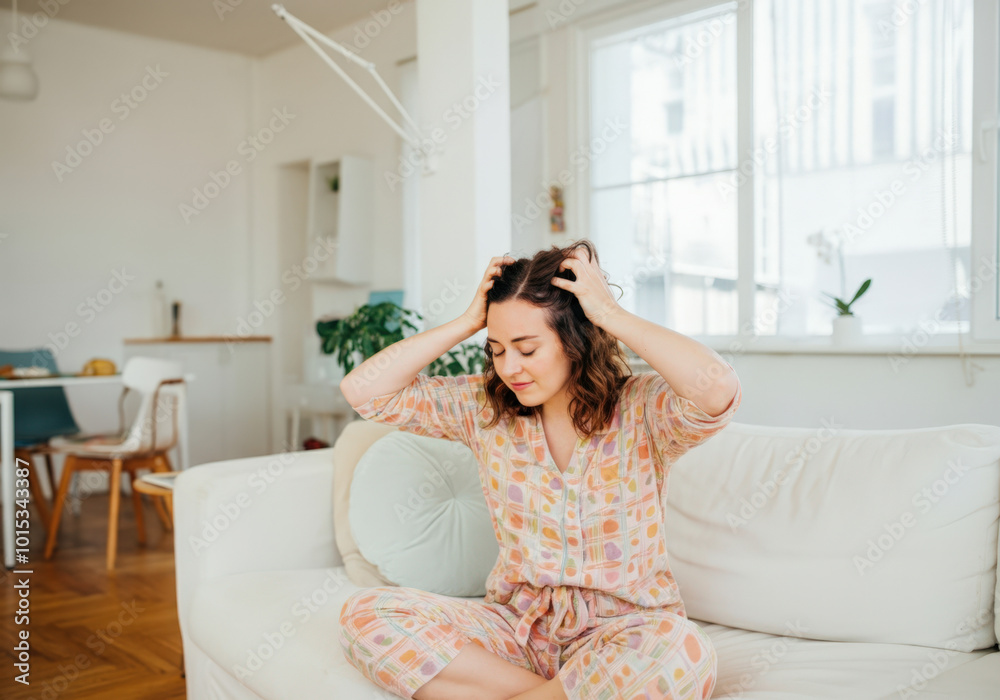 Woman enjoying a relaxing scalp massage while sitting on a sofa at home Woman enjoying a relaxing scalp massage while sitting on a sofa at home