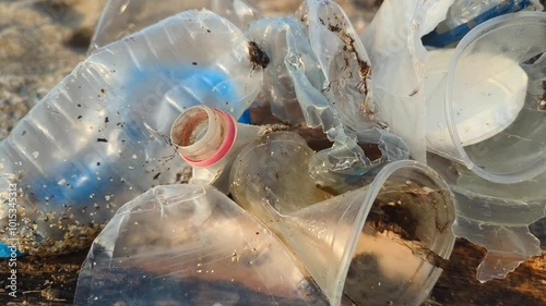 Plastic items scattered on the sandy beach by the sea. An ecological issue that we create ourselves while enjoying nature.