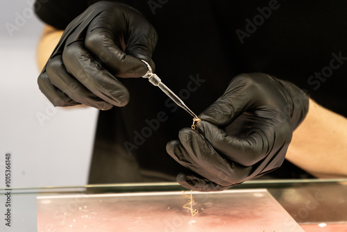 Lady's hands cleaning golden necklace with chemicals in pawnshop or jewelry shop. Customers buy and sell precious metals and jewels.