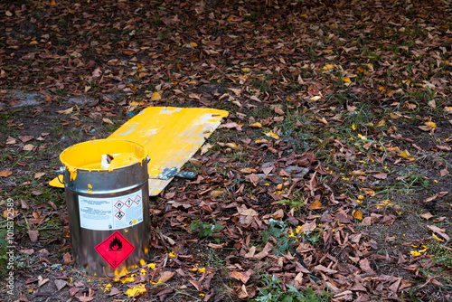 A can of yellow paint among the autumn leaves